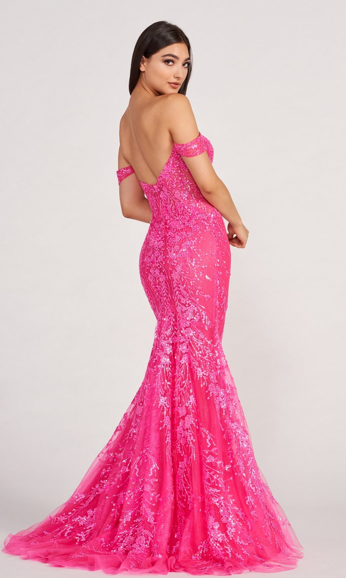 A woman in a Lace-Embroidered Off-Shoulder Long Mermaid Gown stands with her back turned, looking over her shoulder—an unforgettable prom dress moment.